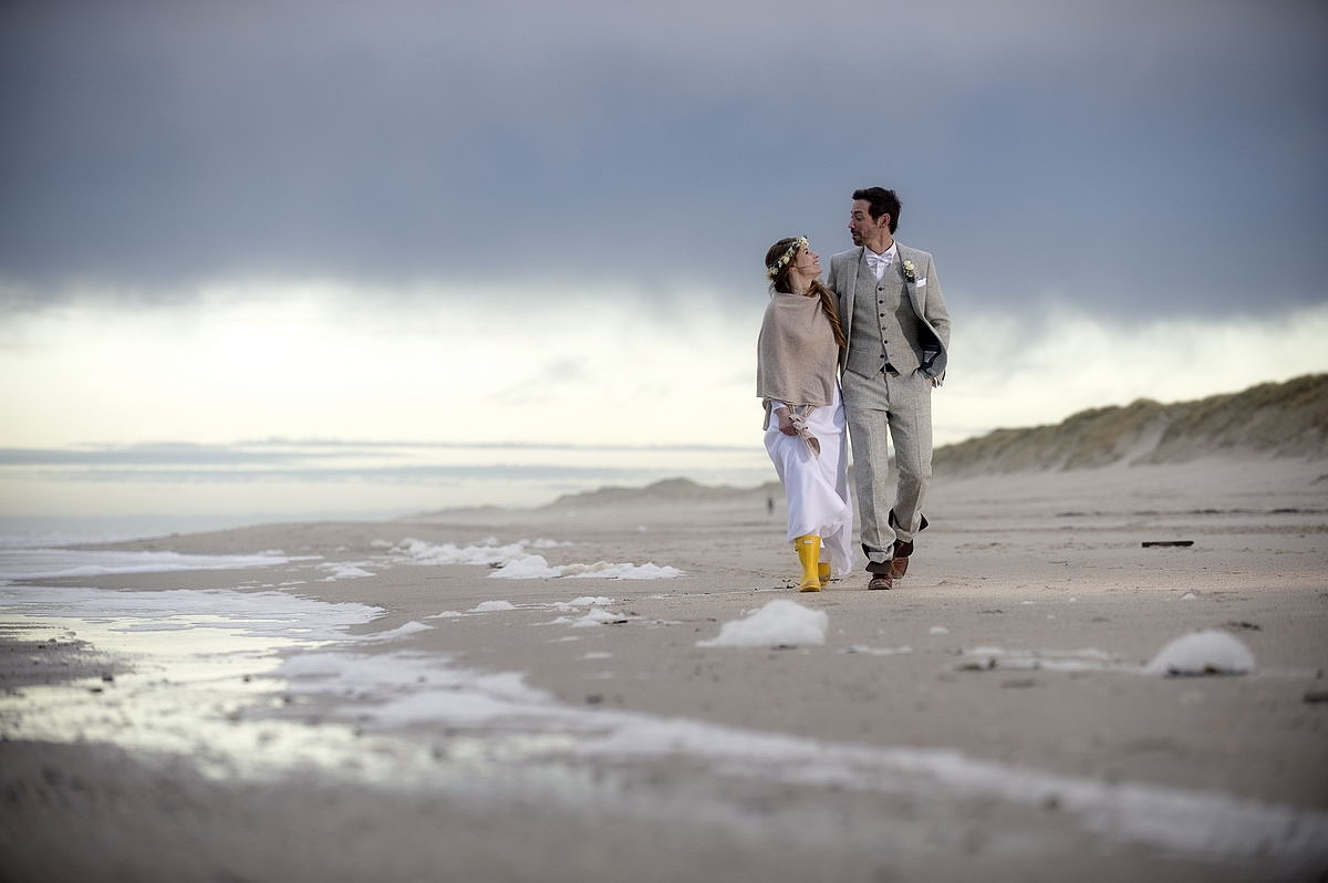 Ein Hochzeitspaar spaziert am Strand von Sylt in herbstlichen kaltem Wetter